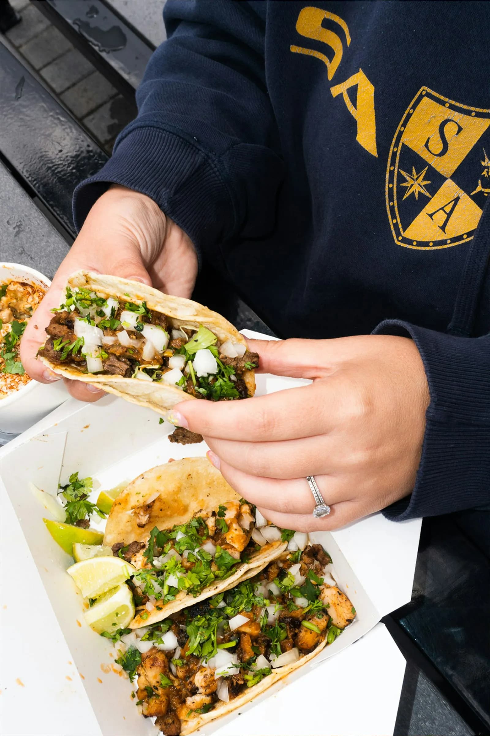 Una mano sostiene un taco de carne con cebolla y cilantro