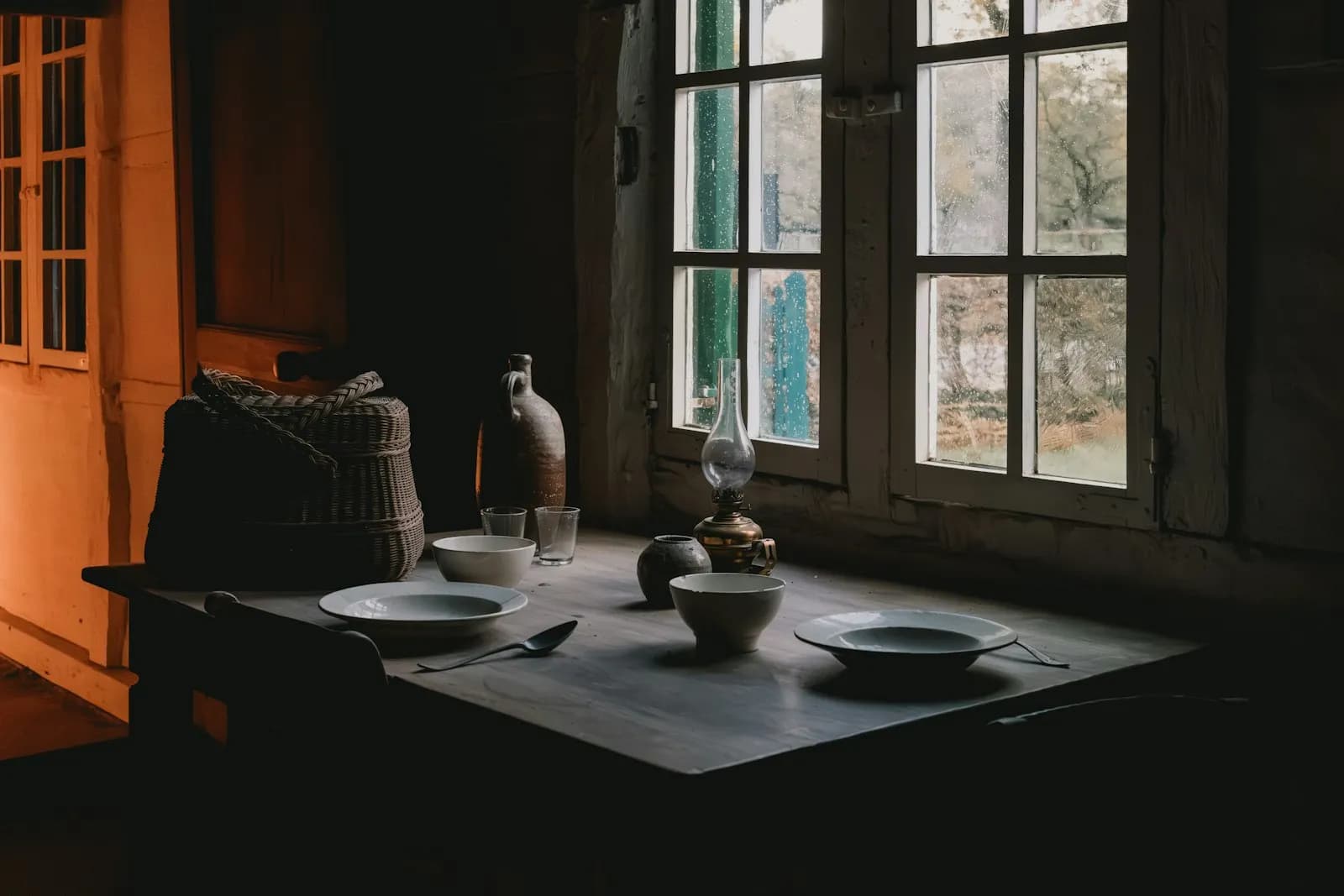 Mesa con platos y cuencos junto a una ventana por la que entra luz natural