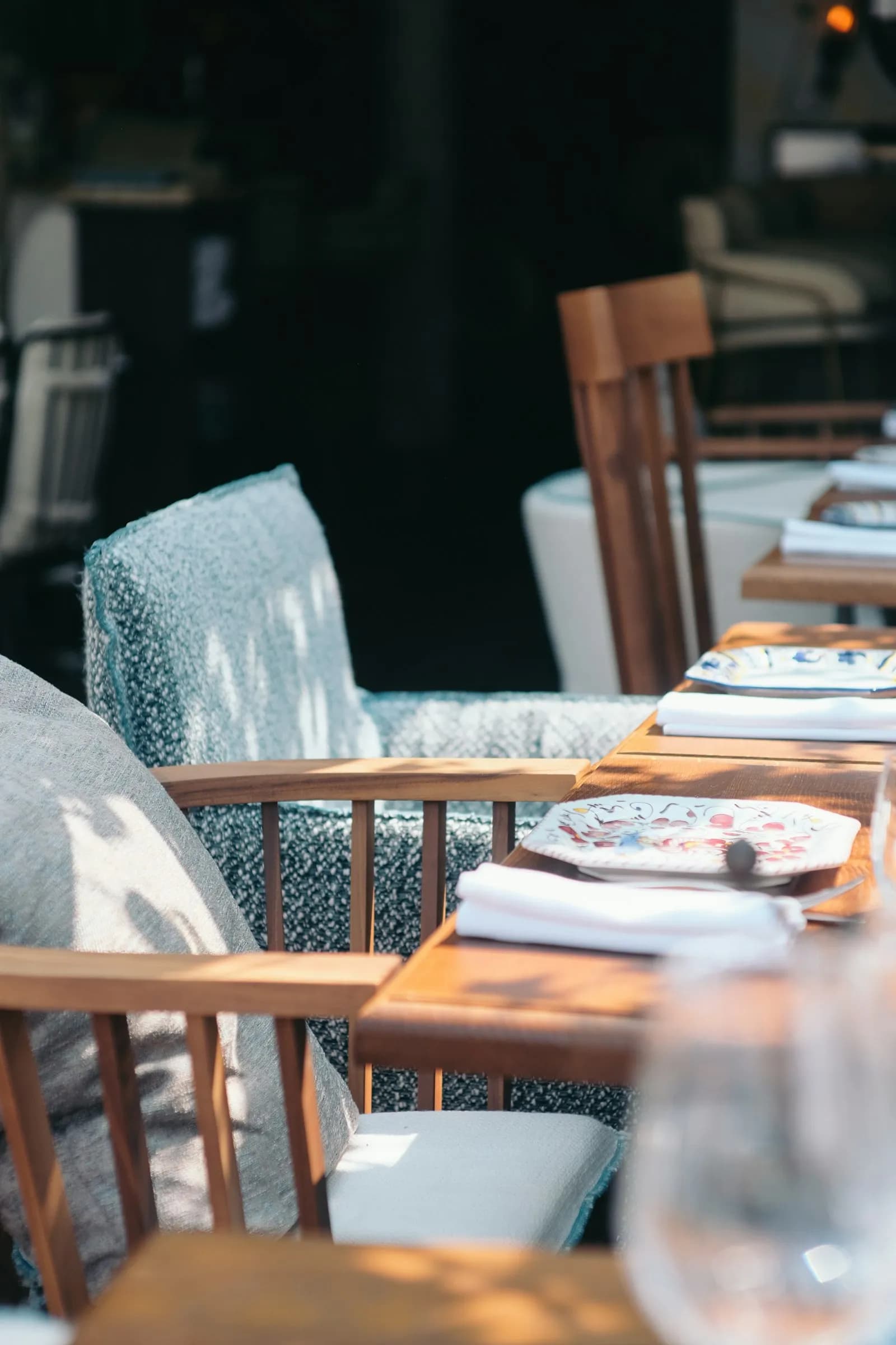 Mesa de terraza con una silla de tela azul y platos sobre la mesa