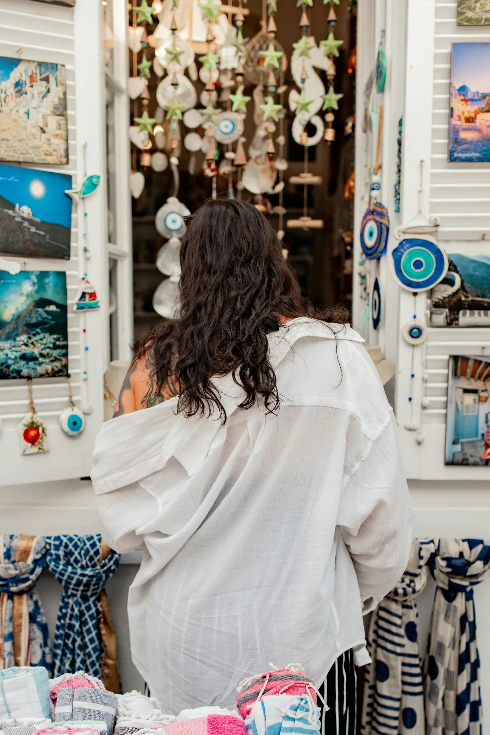 Mujer de espaldas con blusa blanca en una tienda con adornos en la pared